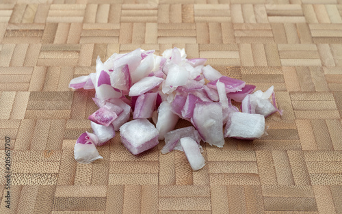A portion of chopped red onions on a bamboo cutting board.