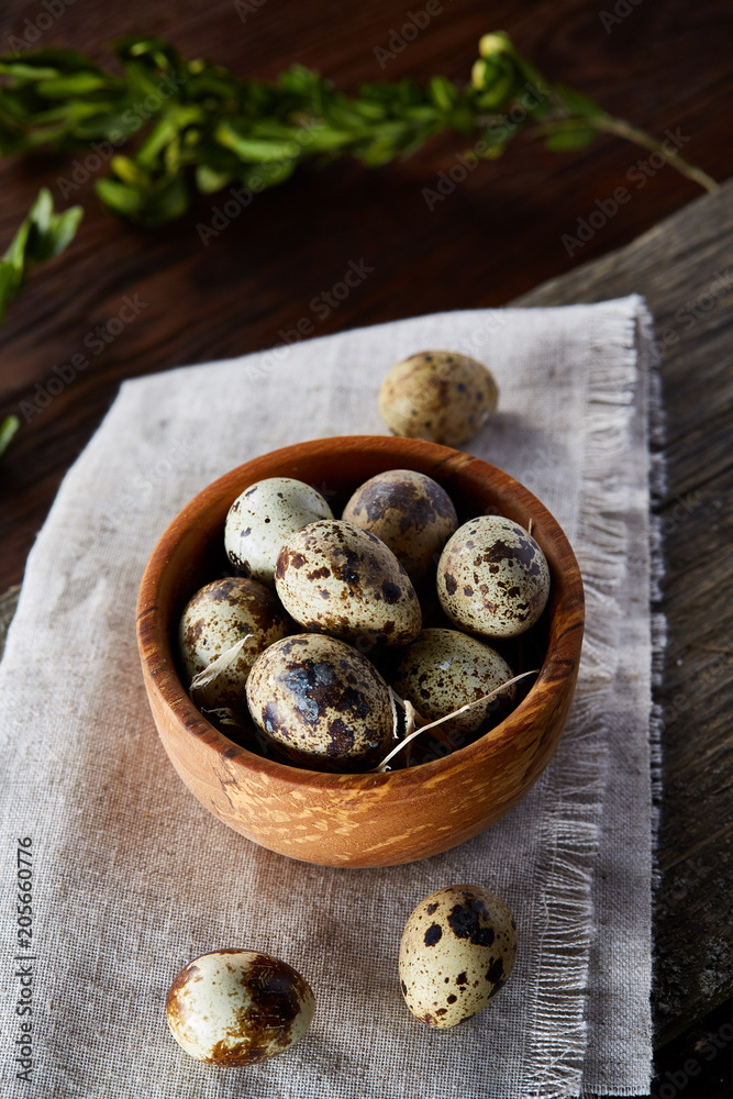 Bowl with eggs quail, eggs on a homespun napkin, boxwood on wooden background, close-up, selective focus Bowl with eggs quail, eggs on a homespun napkin, boxwood on wooden background, close-up, selective focus