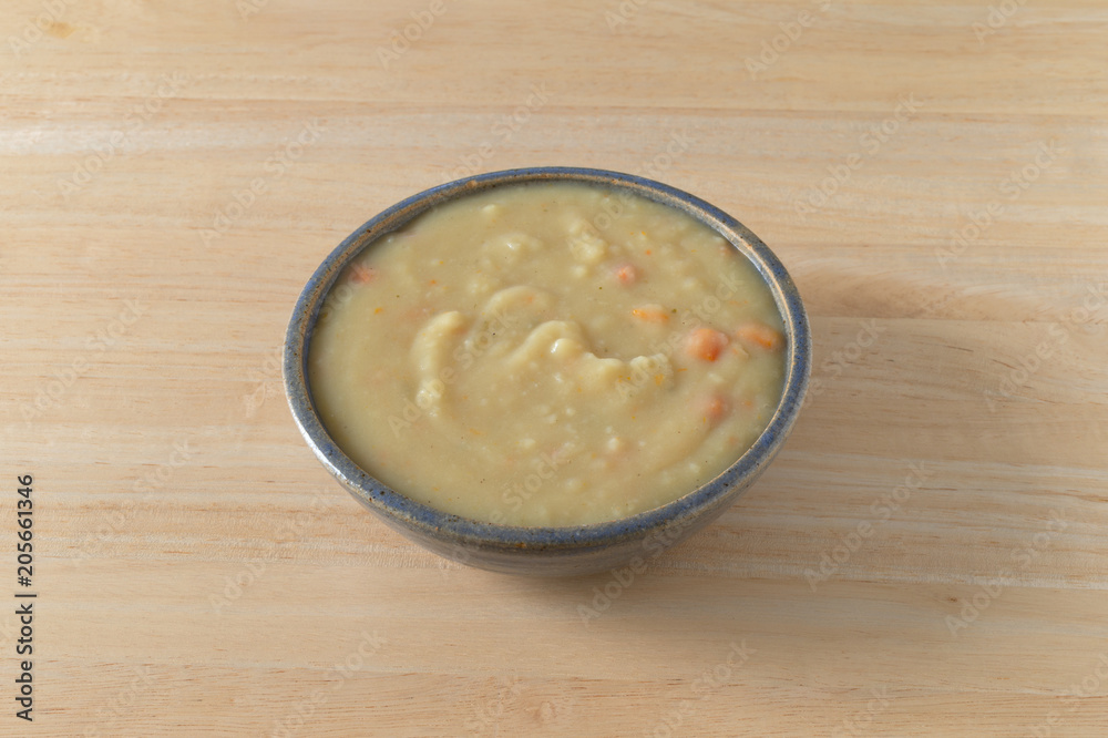 Home style potato soup in a stoneware bowl on a table illuminated with natural light. Home style potato soup in a stoneware bowl on a table illuminated with natural light.