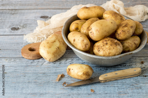 Young early potatoes in an old aluminum bowl on a wooden table. 