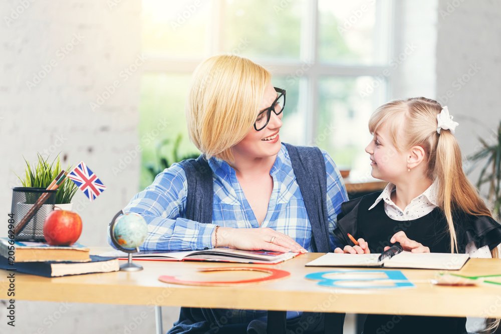 English language female teacher studying with smart kid girl in light white classroom, children learning concept English language female teacher studying with smart kid girl in light white classroom, children learning concept