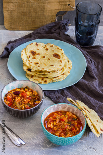 Tortillas with chili con carne. Grey background blue and grey bowls, plates.
