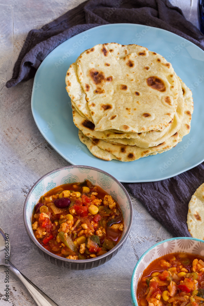 Tortillas with chili con carne. Grey background blue and grey bowls, plates. Tortillas with chili con carne. Grey background blue and grey bowls, plates.