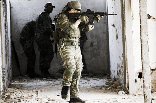 Soldier on move, aim target with red dot rifle