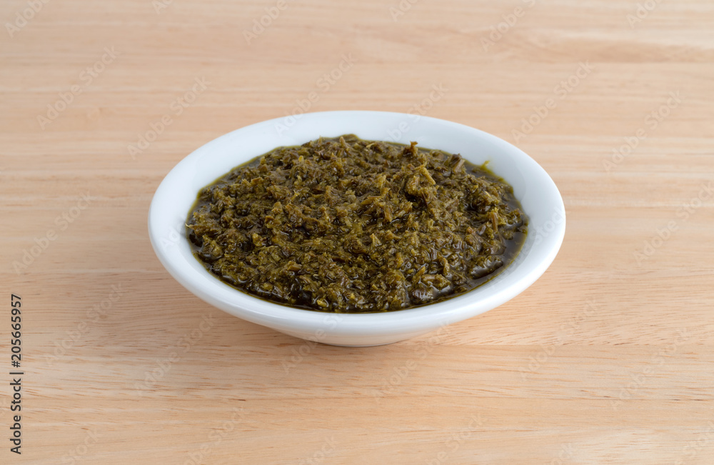 Bowl of chopped parsley in canola oil on a wood table.