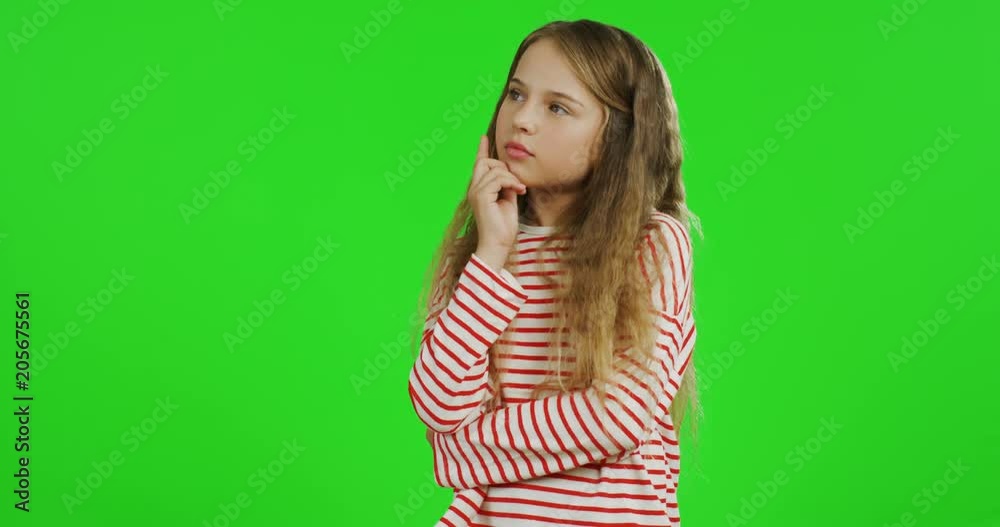 Portrait shot of the cute schoolgirl with long hair standing on the green screen background and thinking. Chroma key Portrait shot of the cute schoolgirl with long hair standing on the green screen background and thinking. Chroma key