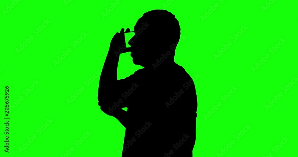 Silhouette of a man standing in the studio while talking on cellphone, shot in 4k resolution with green screen background Silhouette of a man standing in the studio while talking on cellphone, shot in 4k resolution with green screen background