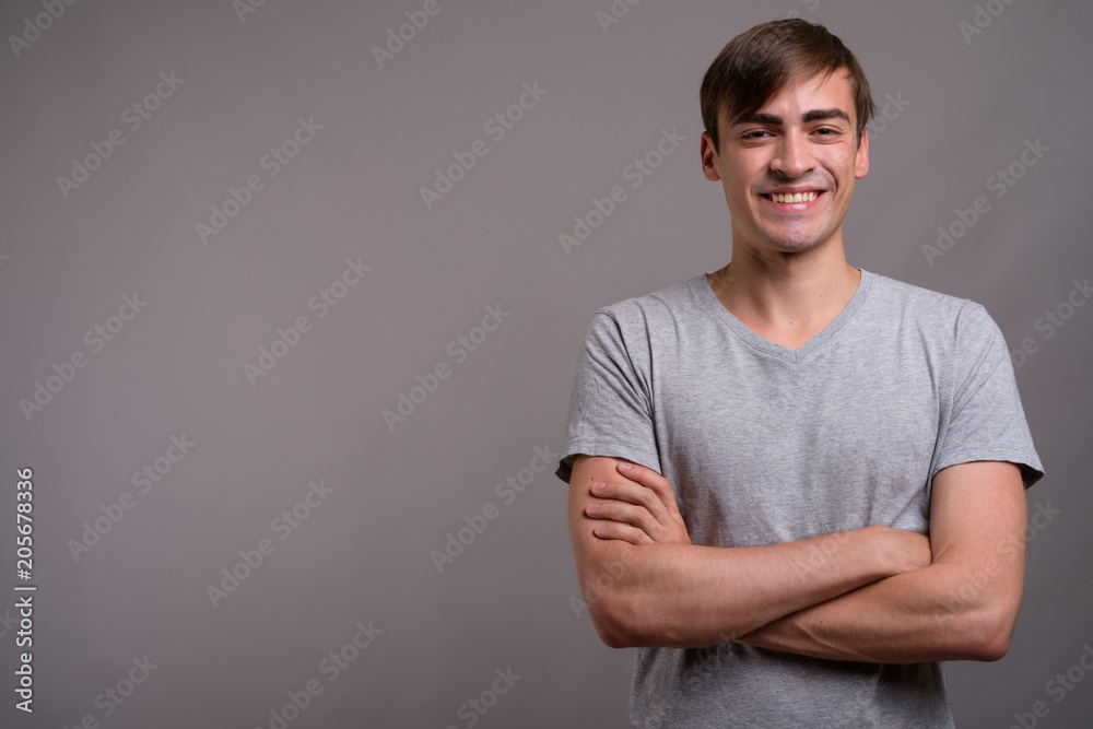 Young handsome man ready for gym against gray background Young handsome man ready for gym against gray background