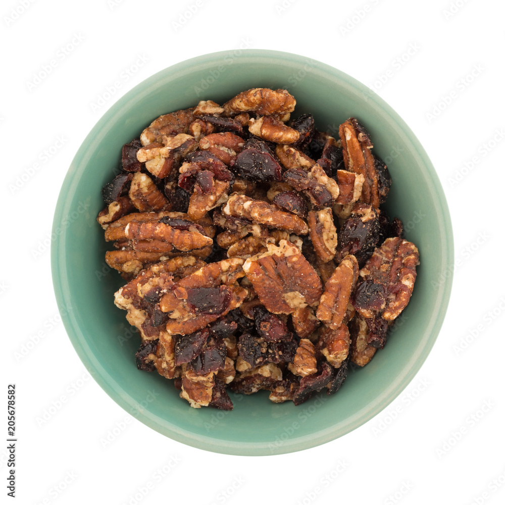 Top view of sugar glazed pecans with dried cranberries in a green bowl isolated on a white background. Top view of sugar glazed pecans with dried cranberries in a green bowl isolated on a white background.