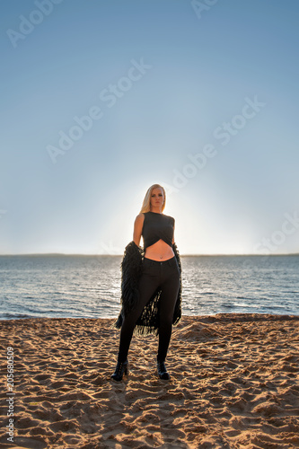 portrait of a seductive blonde girl in black clothes with a sunset lake on a background photo