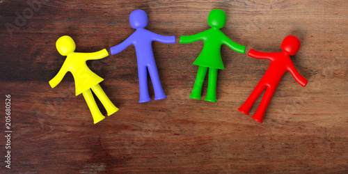 Wallpaper Mural Colorful human figures holding hands laying on wooden background. 3d illustration Torontodigital.ca