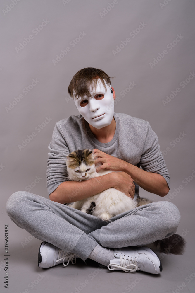 Obraz premium Young handsome man wearing white mask against gray background