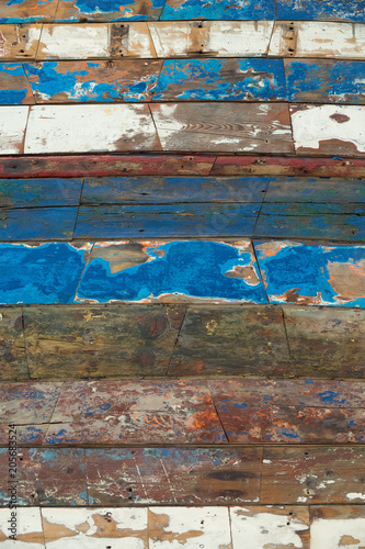 Surface of old and worn out wooden panels painted in several colours with the apaint peeling off