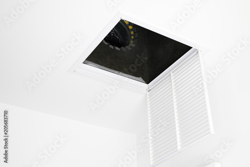 Fotografie HVAC Air Intake Grate Open
White square ceiling furnace air vent grate open, showing inside the duct