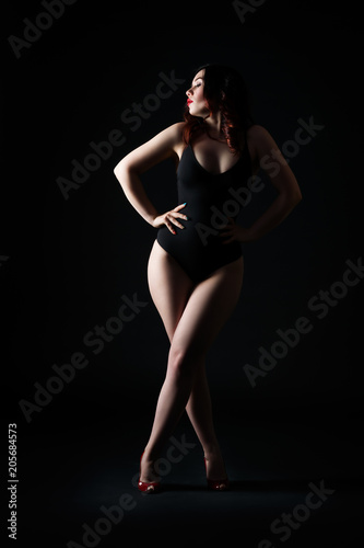 Beautiful sexy woman in bodysuit posing on black background, low key studio shot © staras
