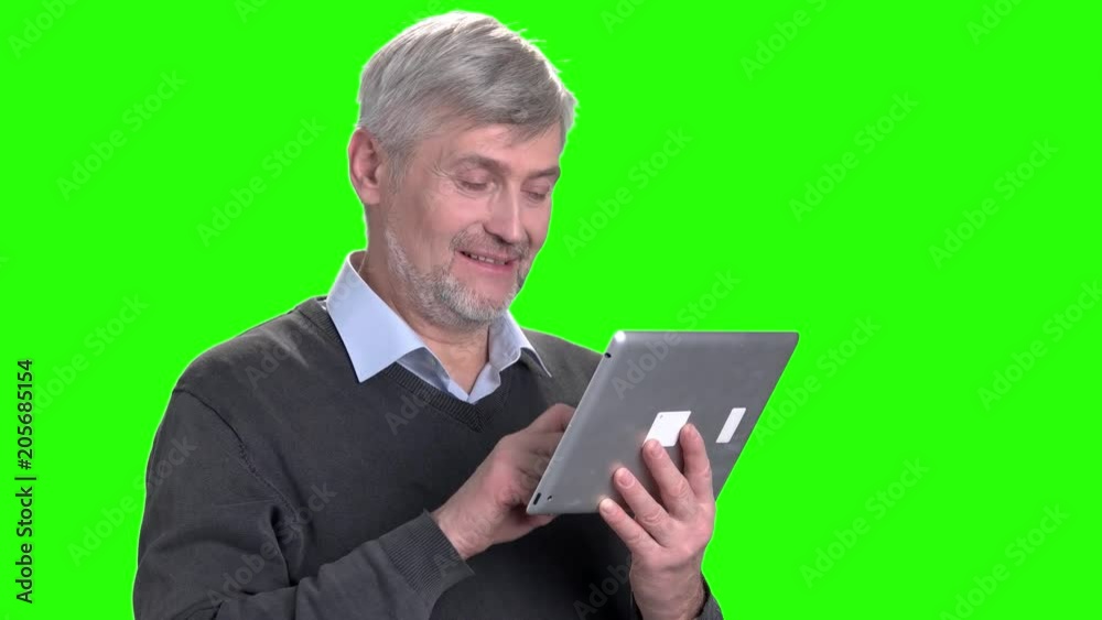 Smiling mature man talking via internet. Handsome senior man using digital tablet on chroma key background. Grandfather talking via skype. People, technology, lifestyle. Smiling mature man talking via internet. Handsome senior man using digital tablet on chroma key background. Grandfather talking via skype. People, technology, lifestyle.