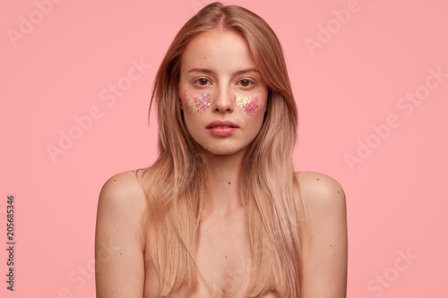Indoor shot of gorgeous female lady poses with naked body decorated with glit...