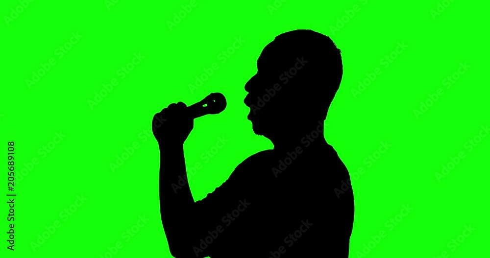 Silhouette of a male classical singer singing with a microphone in the studio, shot in 4k resolution with green screen background Silhouette of a male classical singer singing with a microphone in the studio, shot in 4k resolution with green screen background