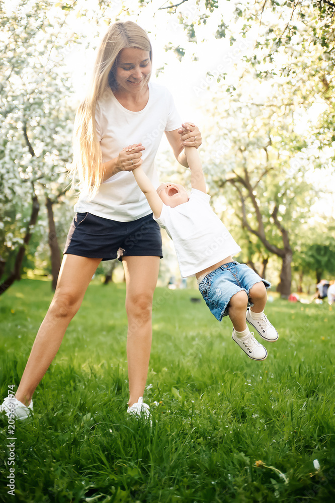 Young beautiful mother playing walks with her child in the summer in the park. The concept of a family and a healthy lifestyle Young beautiful mother playing walks with her child in the summer in the park. The concept of a family and a healthy lifestyle