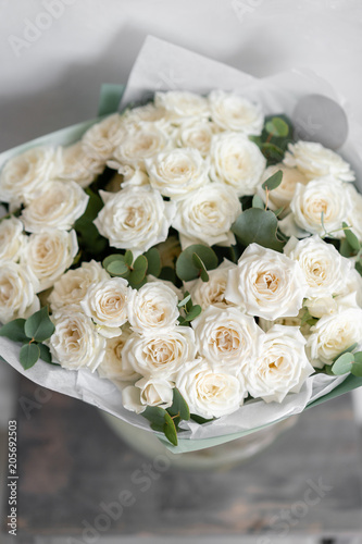 white spray roses. Bouquet of beautiful flowers on wooden table. Floristry concept. the work of the florist at a flower shop. Vertical photo © malkovkosta