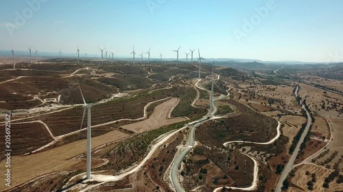 Aerial view of windmills in the mountains, wind power turbines. In the background the sea, shooting from right to left.