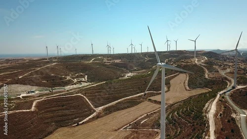 Aerial view of windmills in the mountains, wind power turbines. Wind turbine close-up against the background of the sea and mountains.
