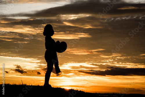 Silhouette Relax and freetime women on the hill and river over orange sunset background.