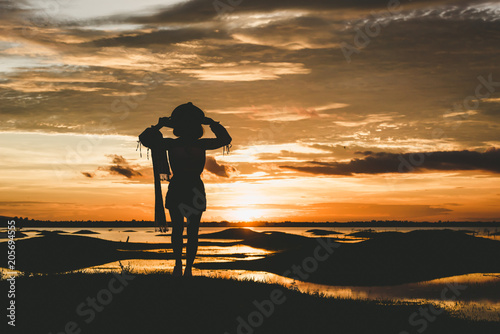 Silhouette Relax and freetime women on the hill and river over orange sunset background.
