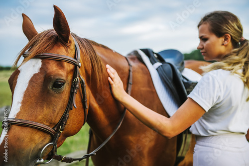 A woman jockey strokes a horse after a horse race.