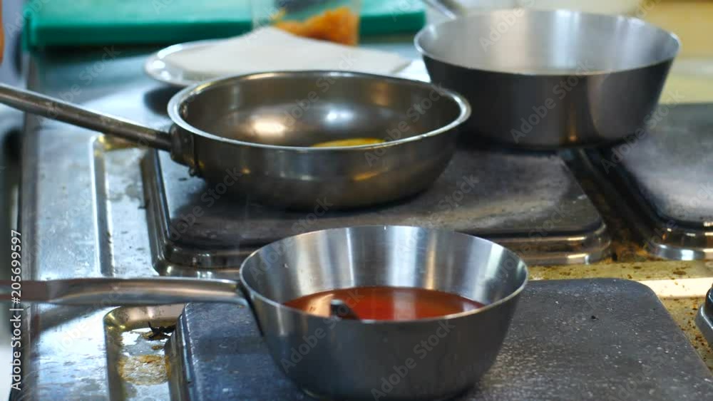 The chef prepares a dish in the kitchen of the restaurant, cooking vegetables, zucchini, prigoshotovlenie sauce, side view close up The chef prepares a dish in the kitchen of the restaurant, cooking vegetables, zucchini, prigoshotovlenie sauce, side view close up