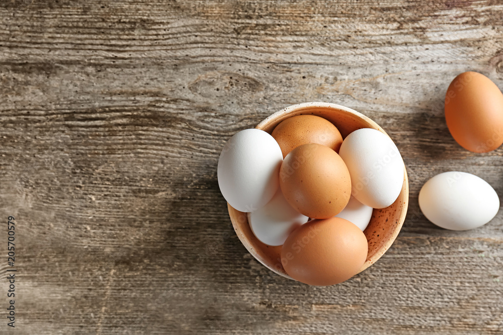 Bowl with chicken eggs on wooden table Bowl with chicken eggs on wooden table