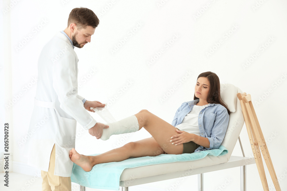 Doctor putting patient's leg in plaster  at clinic