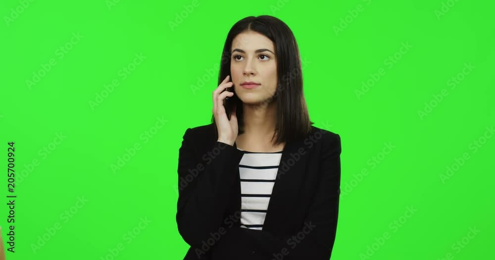 Portrait shot of the young charming woman in the black suit talking on the phone on the chroma key background. Green screen. Portrait shot of the young charming woman in the black suit talking on the phone on the chroma key background. Green screen.