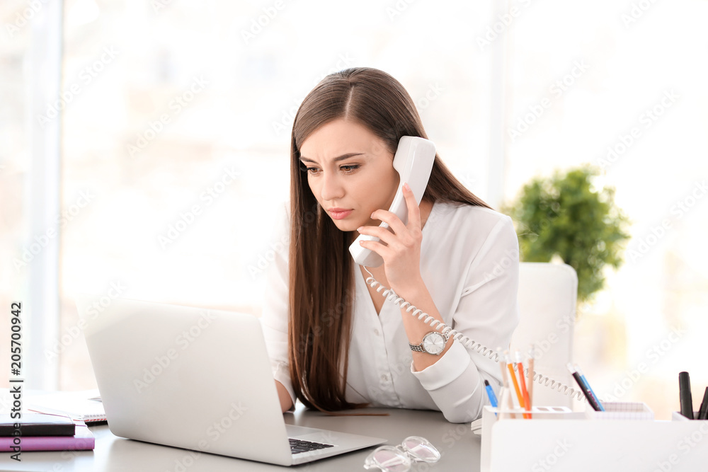 Young woman talking on phone at workplace Young woman talking on phone at workplace