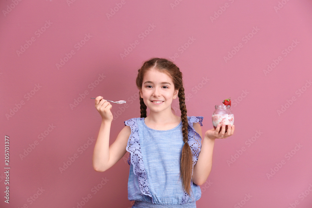 Cute girl eating tasty yogurt on color background Cute girl eating tasty yogurt on color background