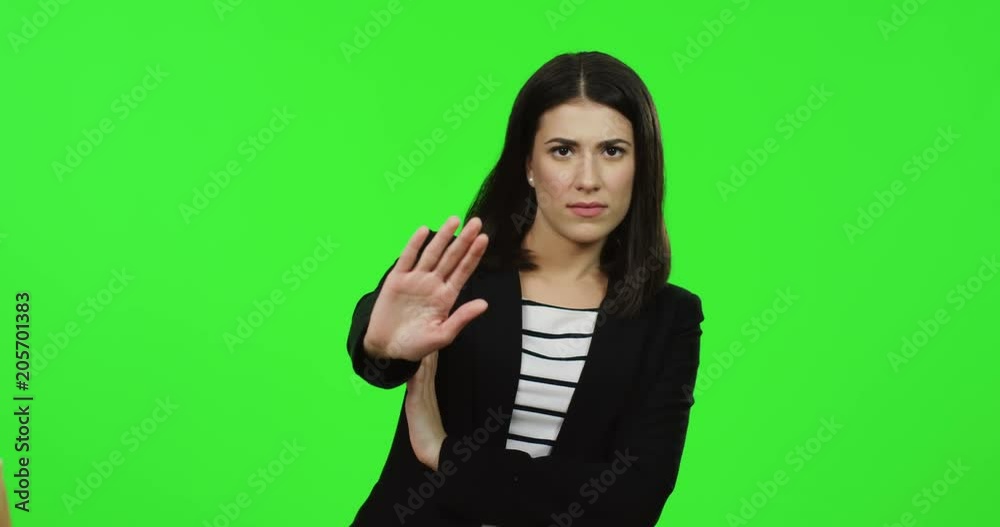 Close up if the charming brunette young woman standing on the chroma key background and doing stop gesture with a hand. Green screen Close up if the charming brunette young woman standing on the chroma key background and doing stop gesture with a hand. Green screen