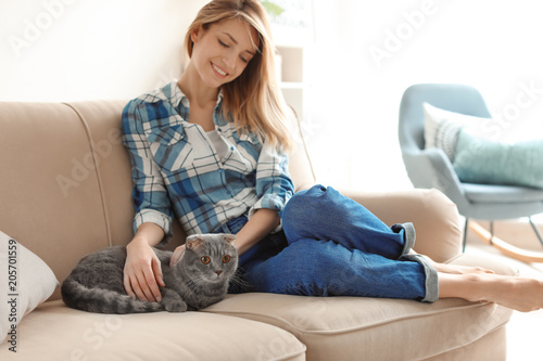 Young woman with her cute pet cat on sofa at home