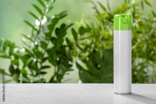 Spray air freshener on table against blurred background