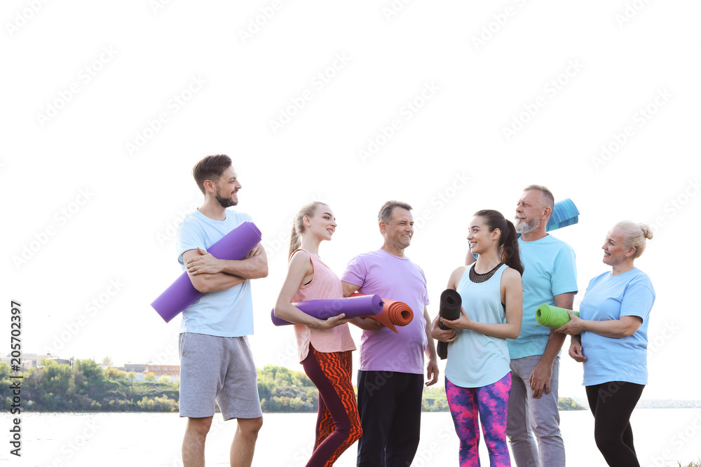 Group of people talking after yoga class near river on sunny day
