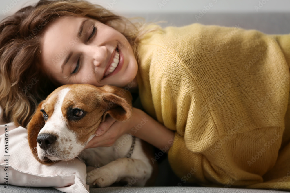 Young woman with her dog resting on sofa at home