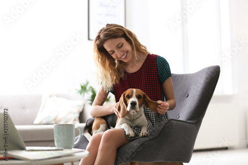 Young woman with her dog sitting in armchair at home © New Africa