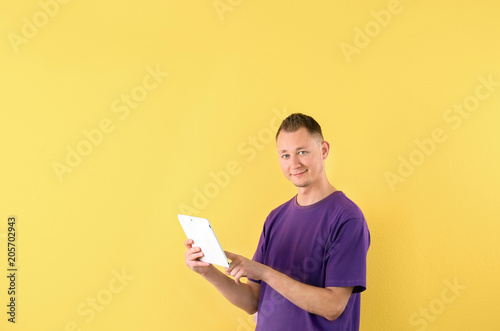 Portrait of handsome man with tablet on color background