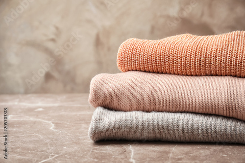 Stack of warm knitted clothes on table