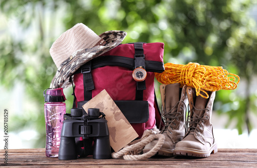 Composition with backpack and camping equipment on table against blurred background