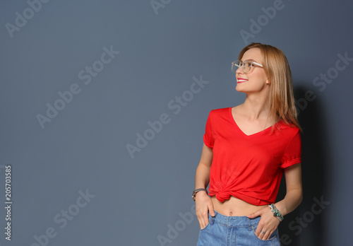 Attractive young woman in stylish outfit on color background