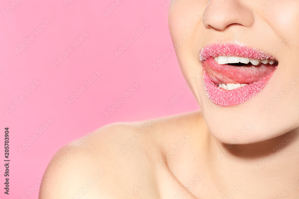 Beautiful young model with sugar lips on color background