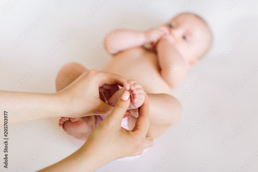 Mother hand massaging foot of her baby on white background