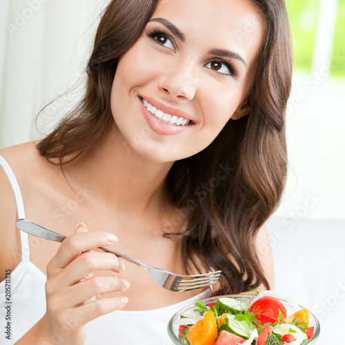 Woman eating salad, indoors