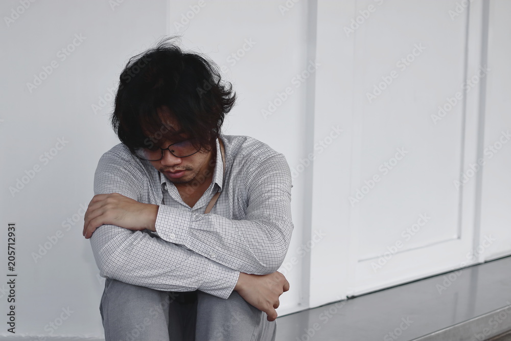 Exhausted tired Asian business man sit and hug his knee at outside office. Exhausted tired Asian business man sit and hug his knee at outside office.