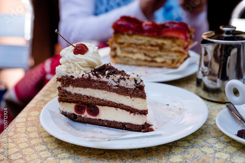 delicious looking french cherry cake with crean and cherry on top, on a white plate. Riquewihr, Alsace.